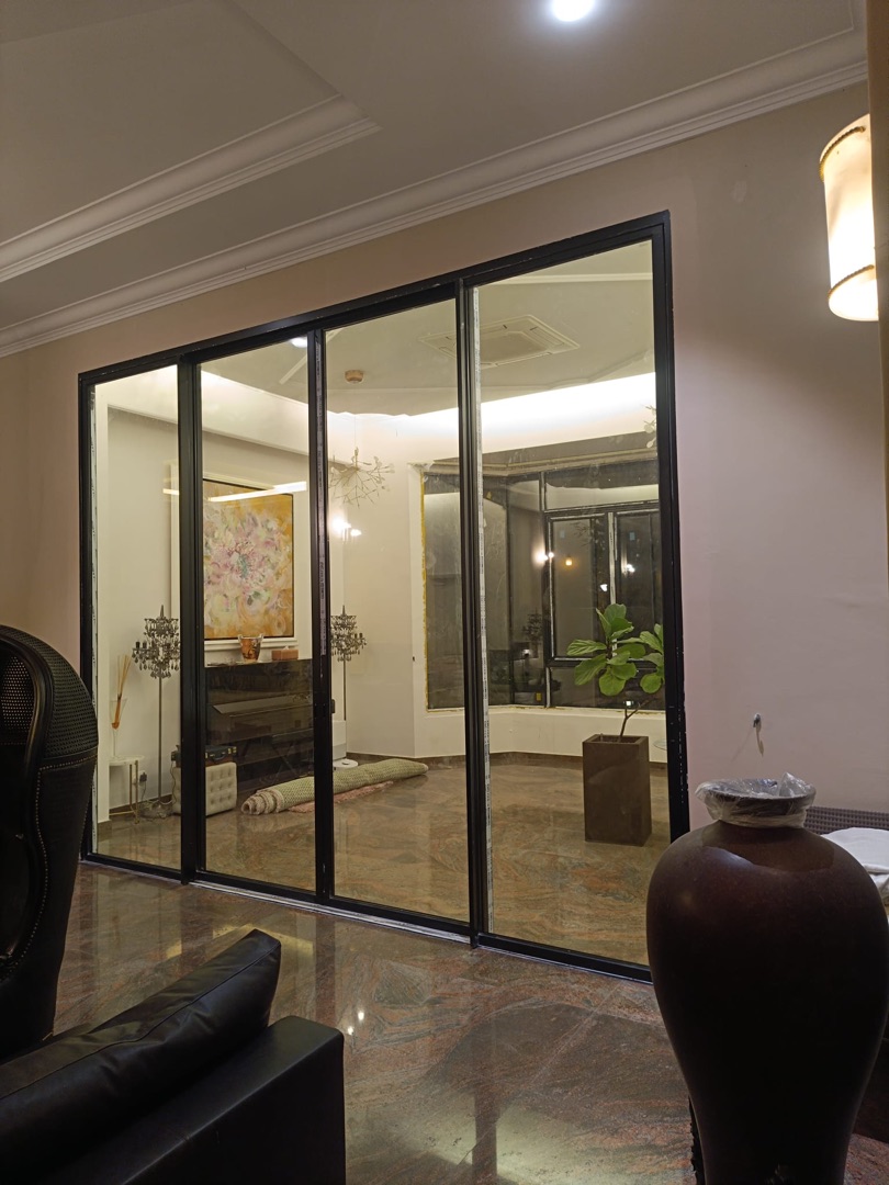 Interior view of EZZO aluminium-framed glass sliding partition between living areas, evening ambience with warm lighting